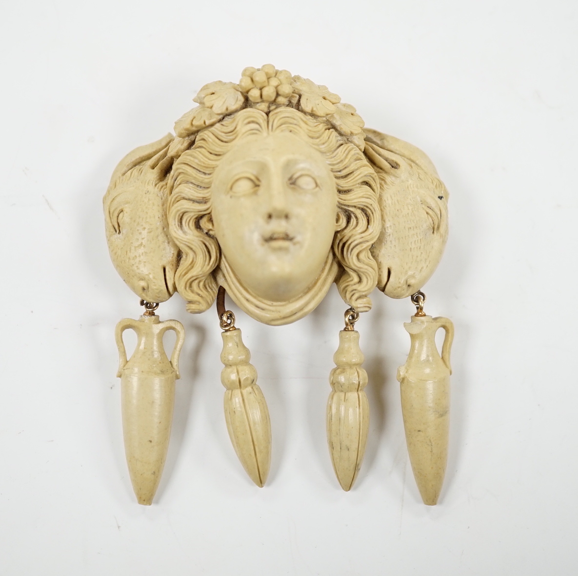 A yellow metal mounted lava drop brooch, modelled as the head of a lady flanked by ram's heads, width 53mm.